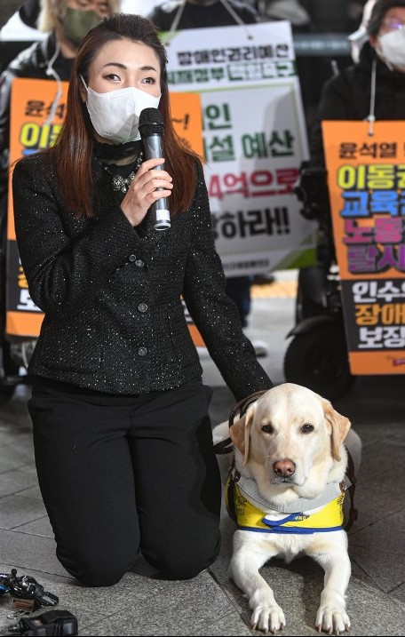 김예지 의원, 왜 박민영 전 대변인을 고소했나? 3 “마스크를 쓴 여성이 안내견과 함께 앉아 마이크를 들고 발언하는 모습”
